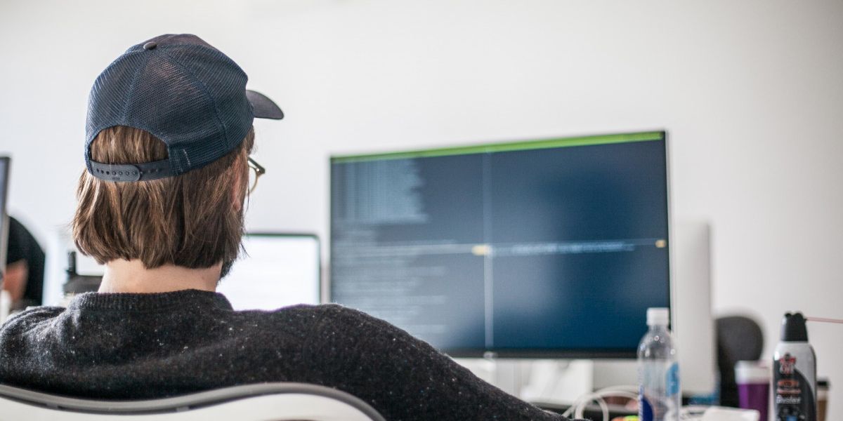 Homem de costas programando no computador.