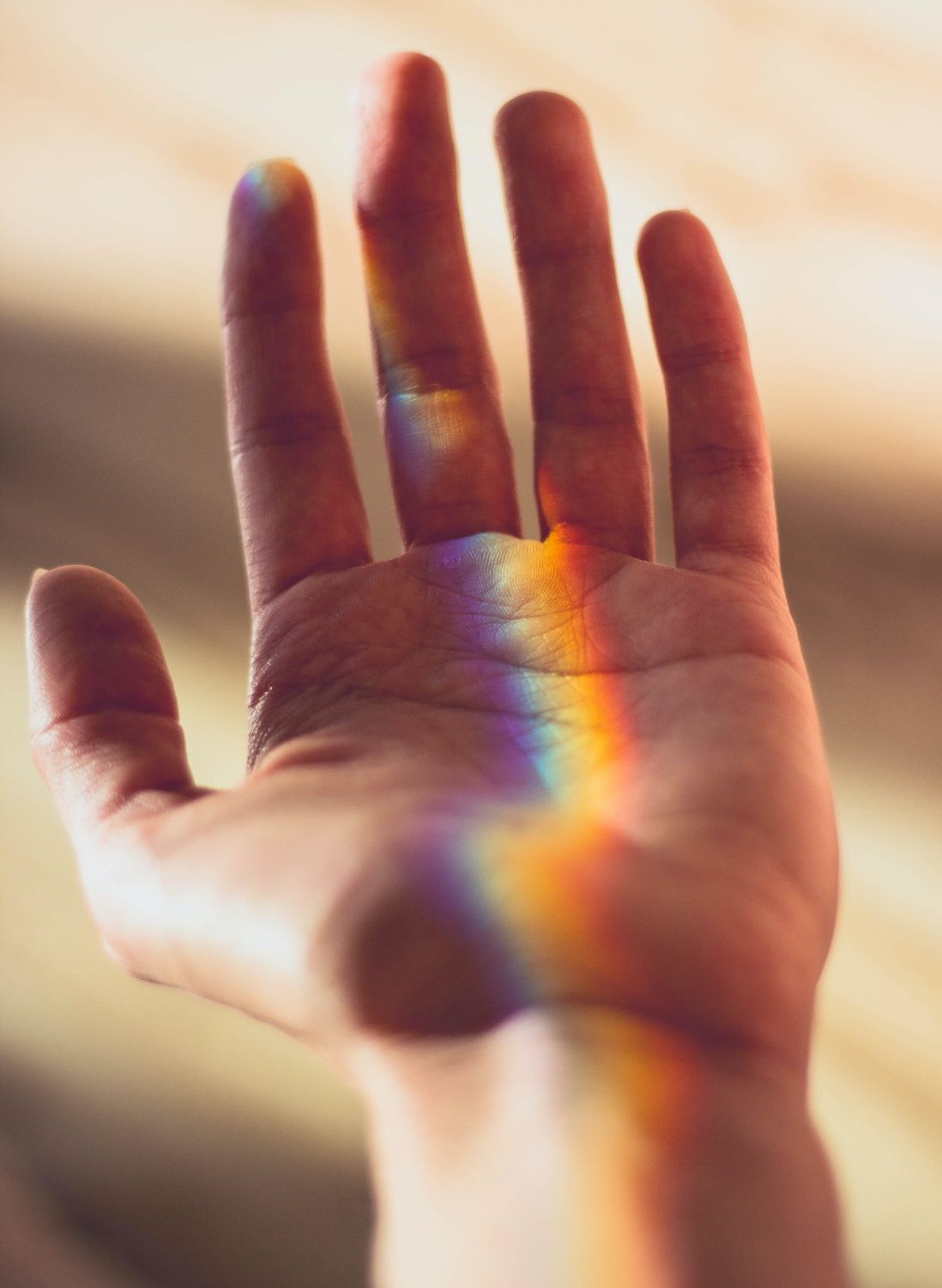 Close up of palm of hand with refracted light of rainbow