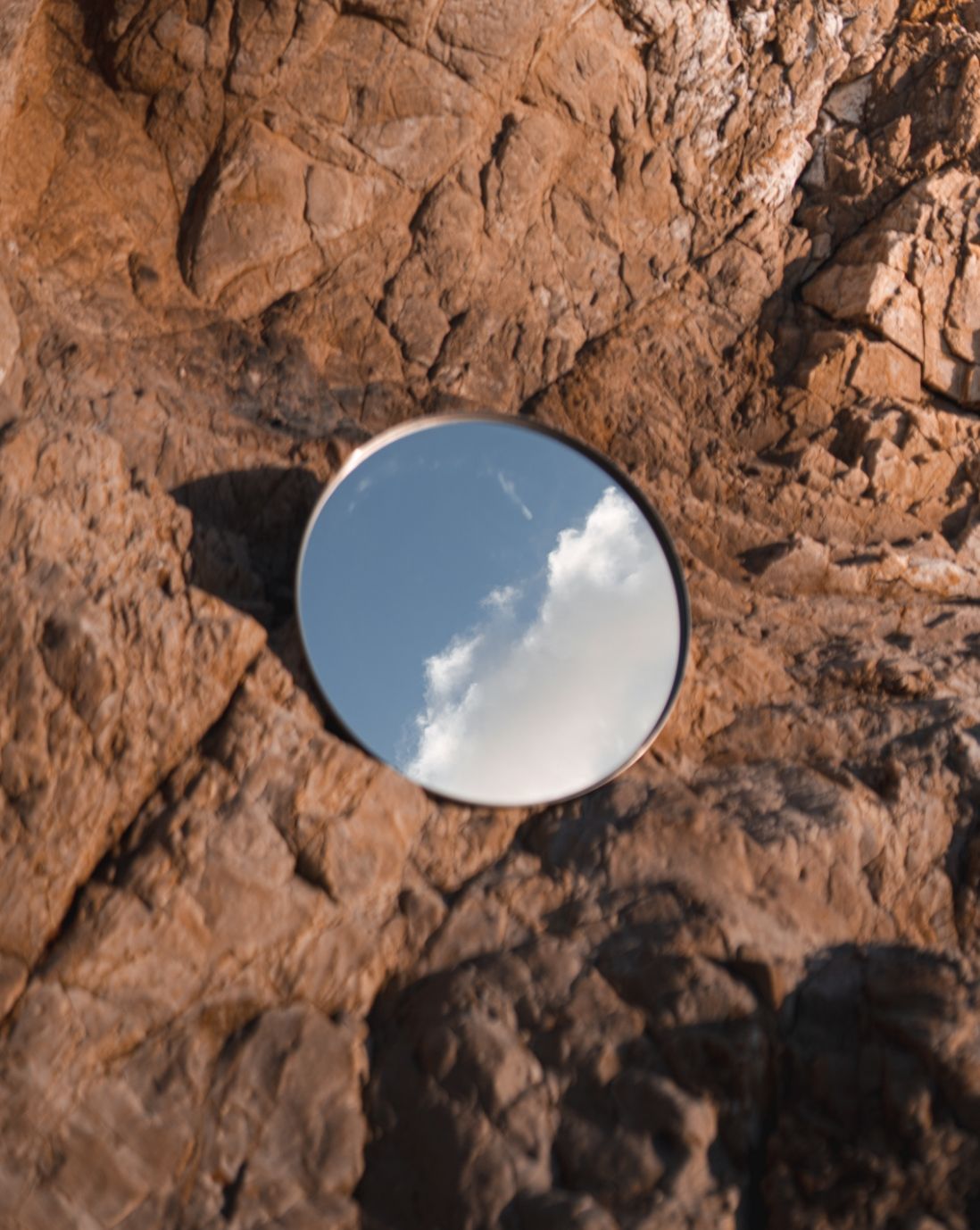 Circle mirror on rocks reflecting the sky