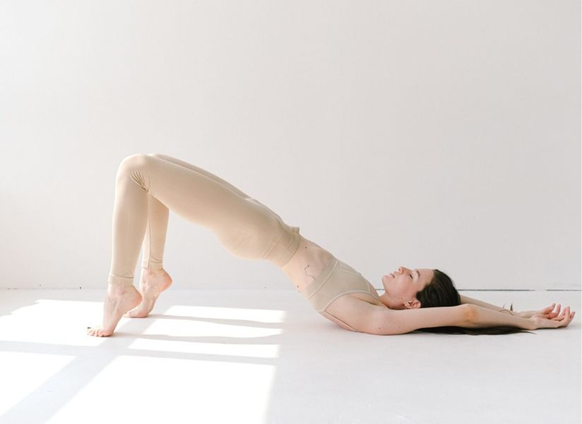 A woman in bridge pose wearing a nude yoga set