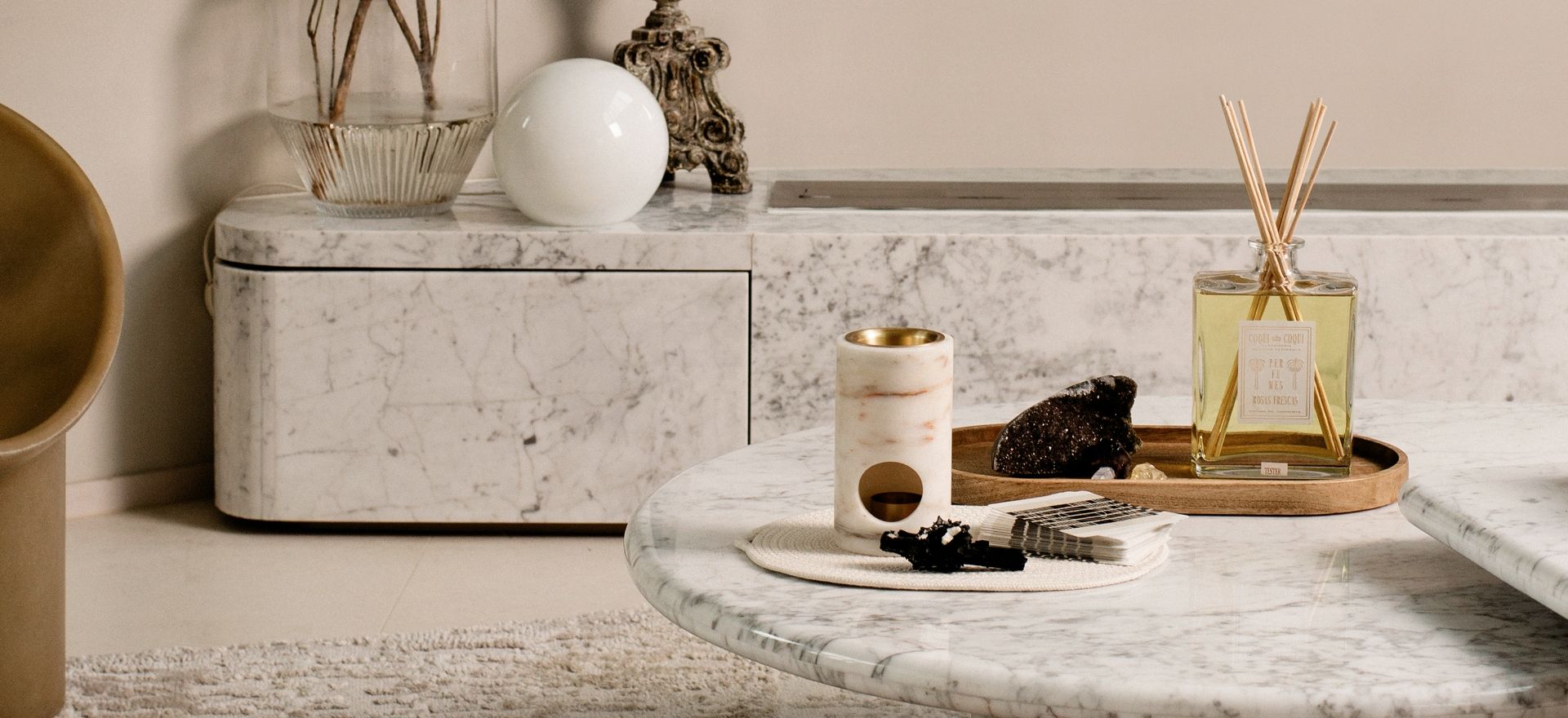 The New Moon Services, wellness products styled on round marble table including a Coqui Coqui diffuser, Addition Studio oil burner and black galaxy amethyst