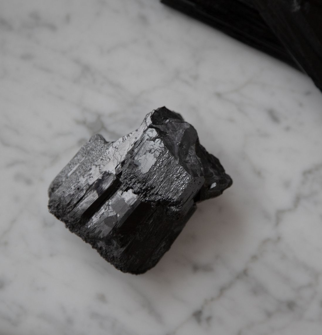 A large black tourmaline on a beautiful grey marble surface