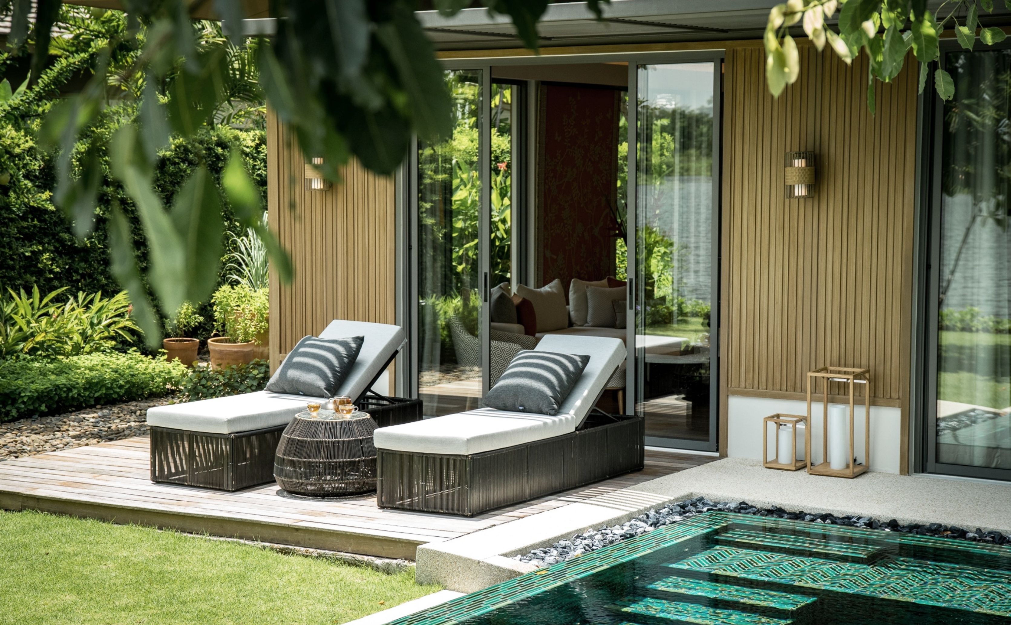 A pool villa with 2 patio lounging chairs surrounded by greenery