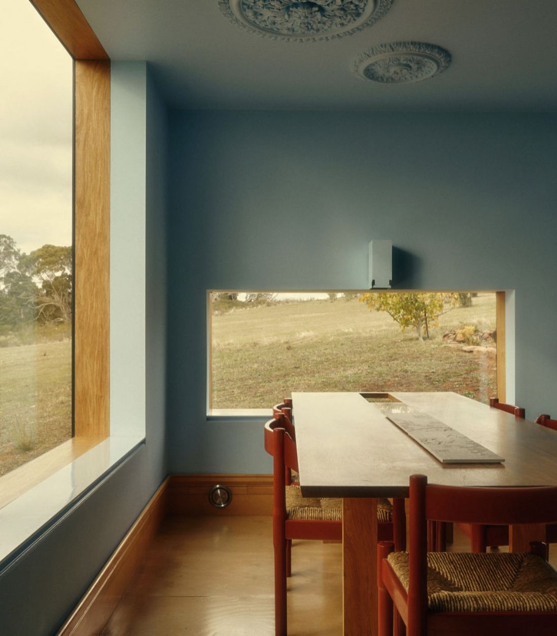 Corner Interior of Daylesford Longhouse with blue walls, large windows and wooden dining table