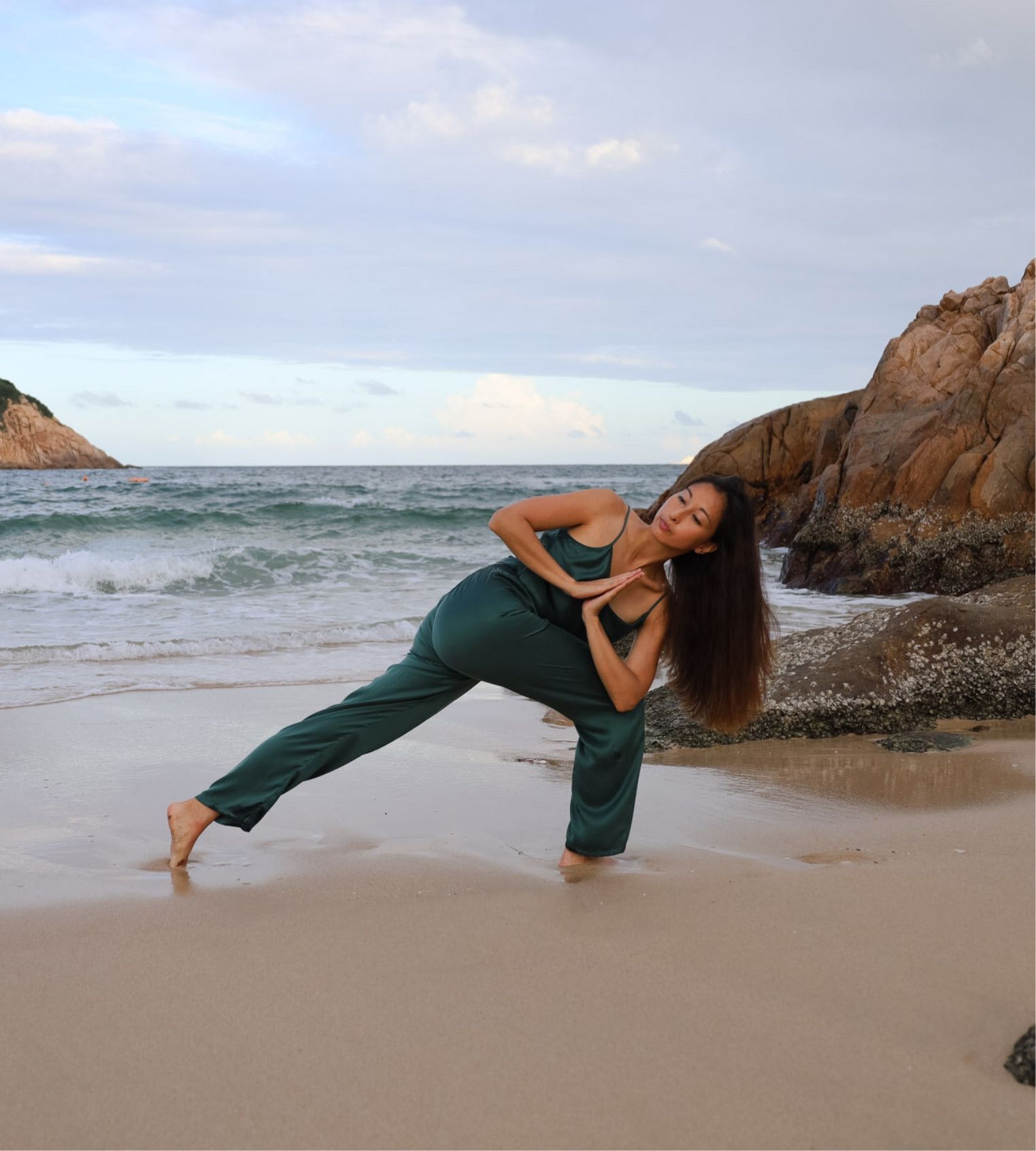 Karina Curlewis performing lunge with prayer twist pose in sandy beach by the ocean