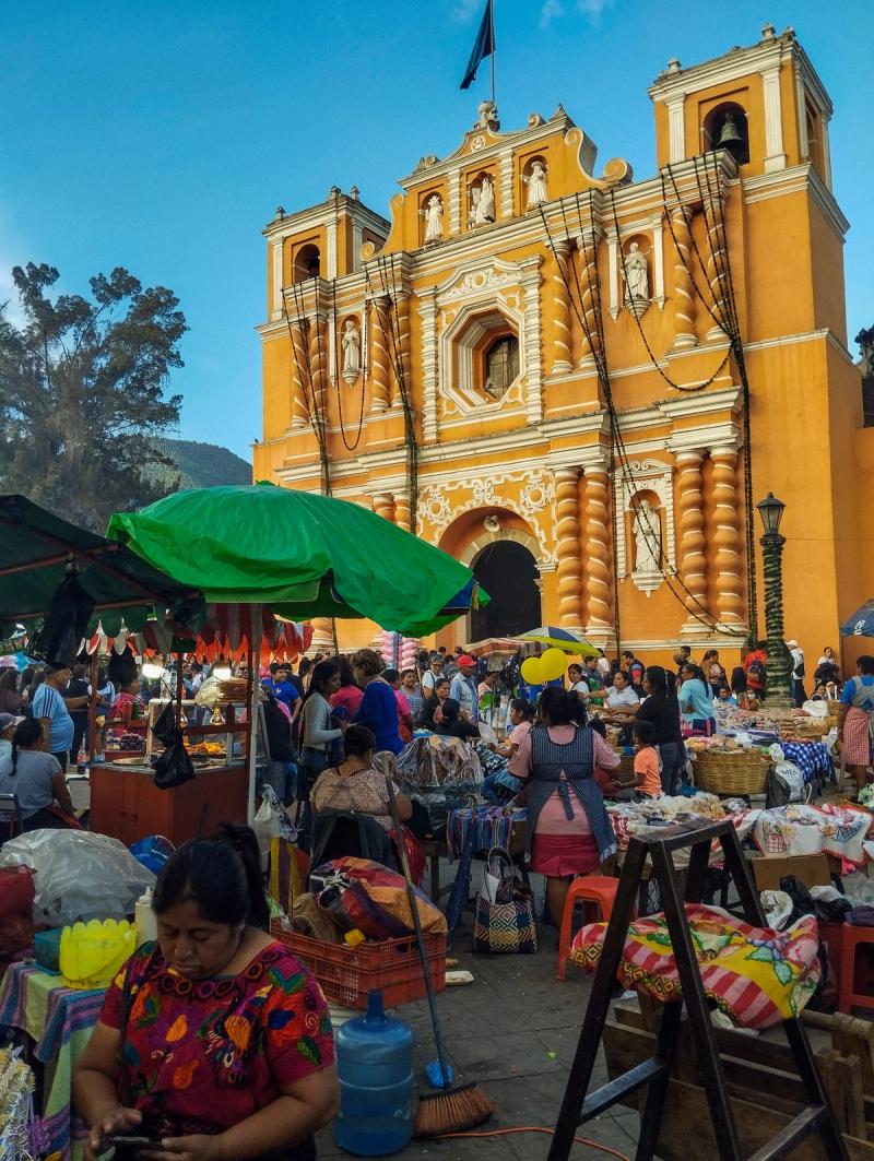 Mercado local frente a una iglesia amarilla en Guatemala