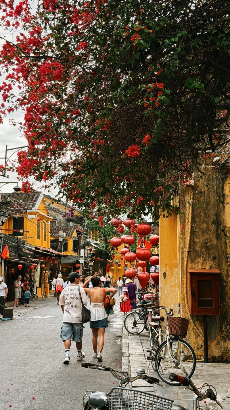 Viajeros paseando entre farolillos y fachadas amarillas en Hoi An
