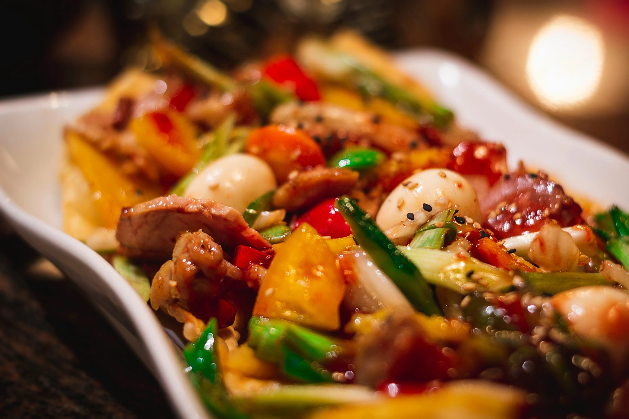 White plate with seafood, vegetables and herbs in warm lighting