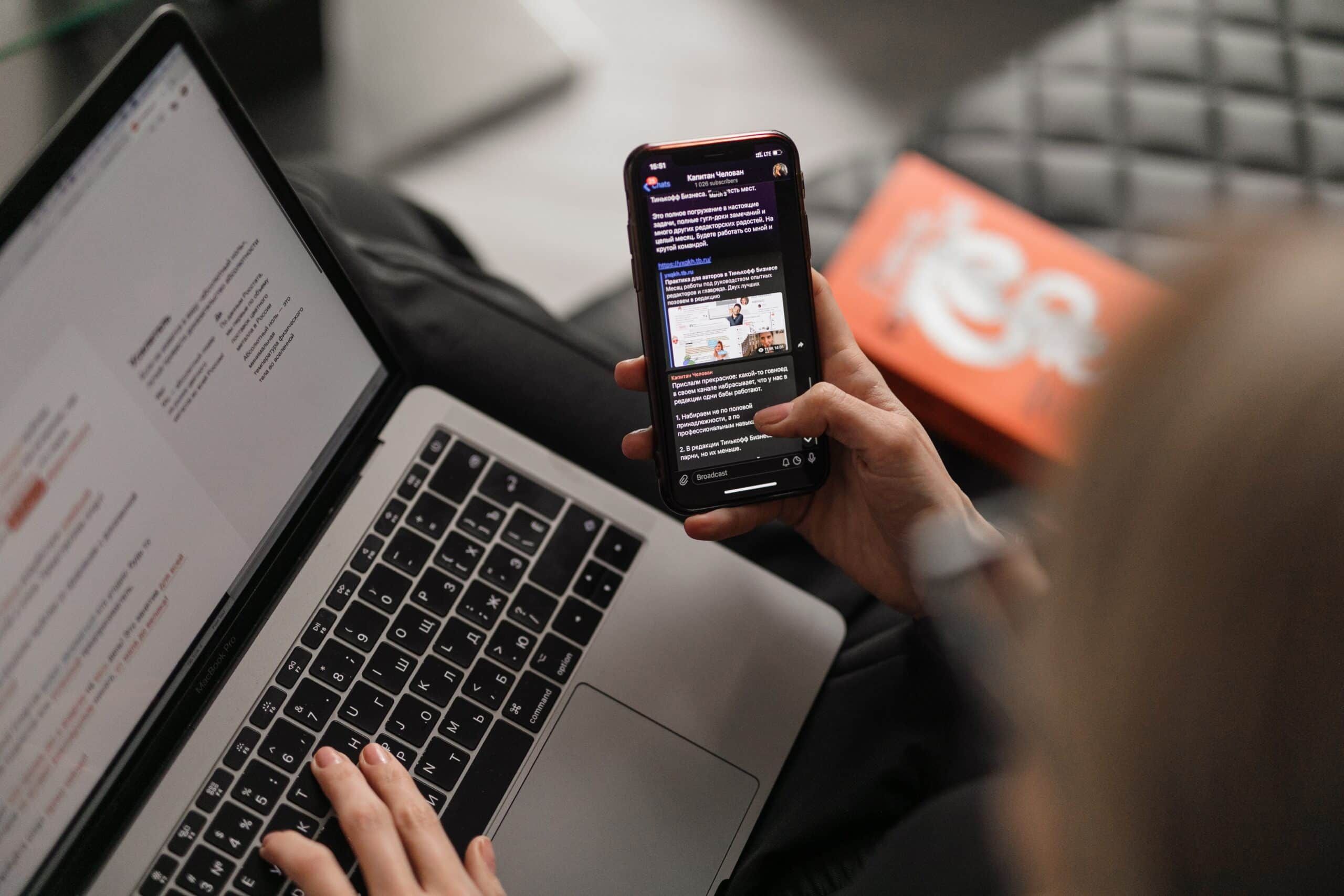 Person multitasking with a laptop and a phone Person multitasking with a laptop and a phone