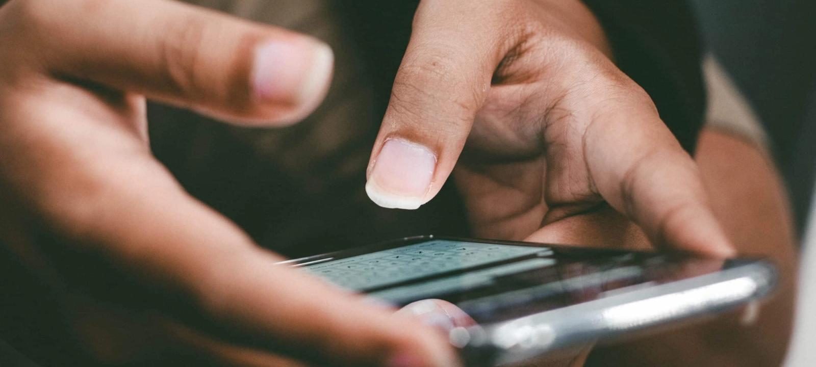 Close-up of hands typing on a smartphone, emphasizing the use of text messaging in personal injury