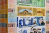 The photo shows an exhibition view. Many coloured banknotes of different currencies are displayed on a wall. On some currencies portraits of people are being depicted. Others show kauri shells or buildings. The names of the currencies are for example Afro or United States of Africa.