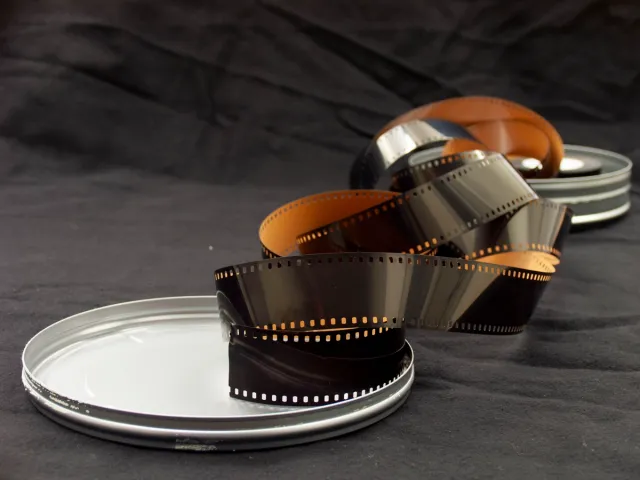 Wywołane negatywy - zwinięta klisza 35 mm obok metalowych puszek na film
