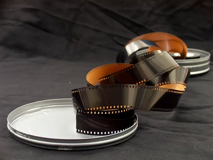 Wywołane negatywy - zwinięta klisza 35 mm obok metalowych puszek na film