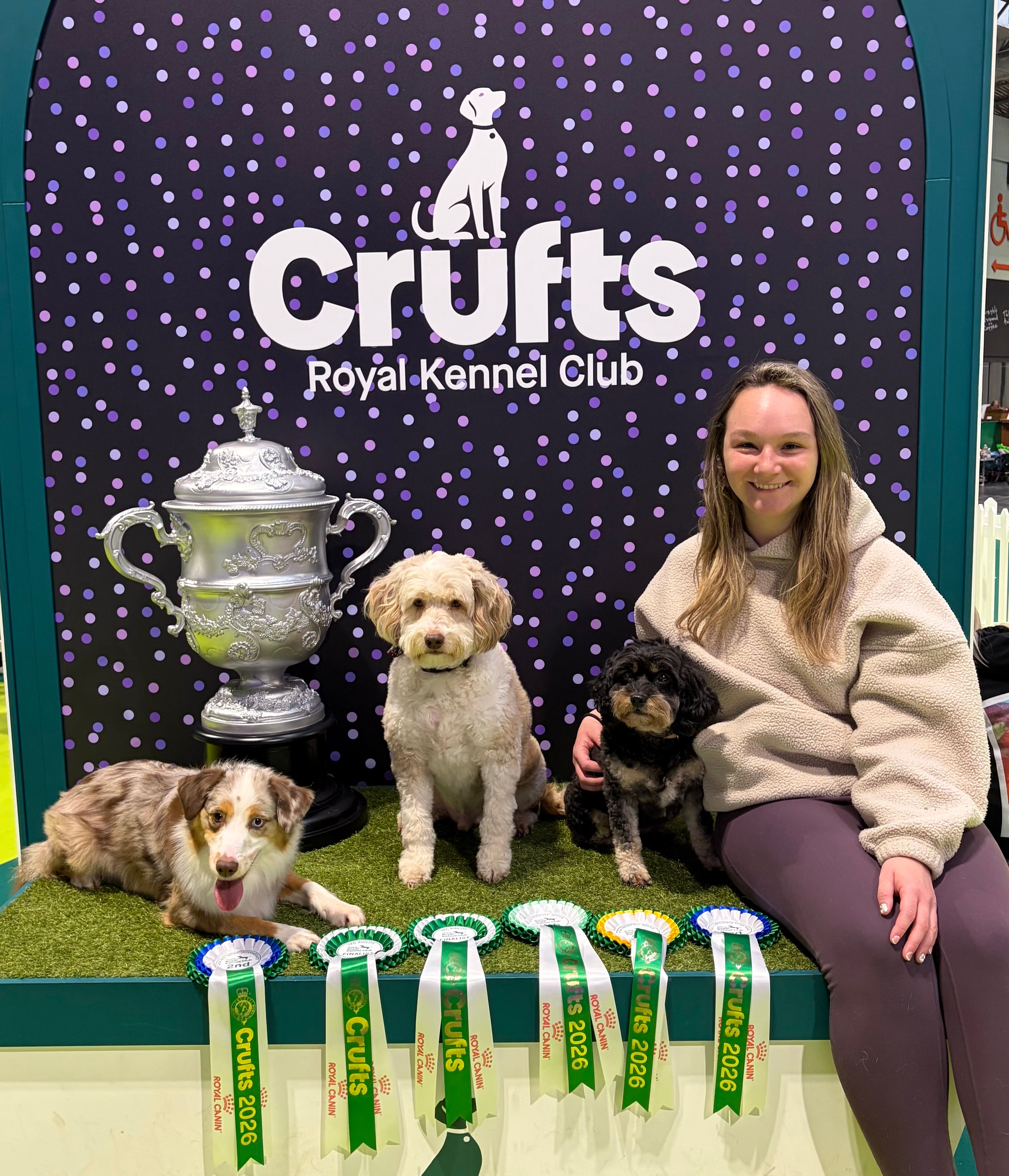 Emma posing at Crufts with her dogs Dream, Athena and Apollo and their rosettes