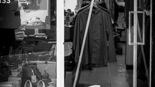 A dog sitting calmly on a lead inside a welcoming shop with a smiling owner nearby