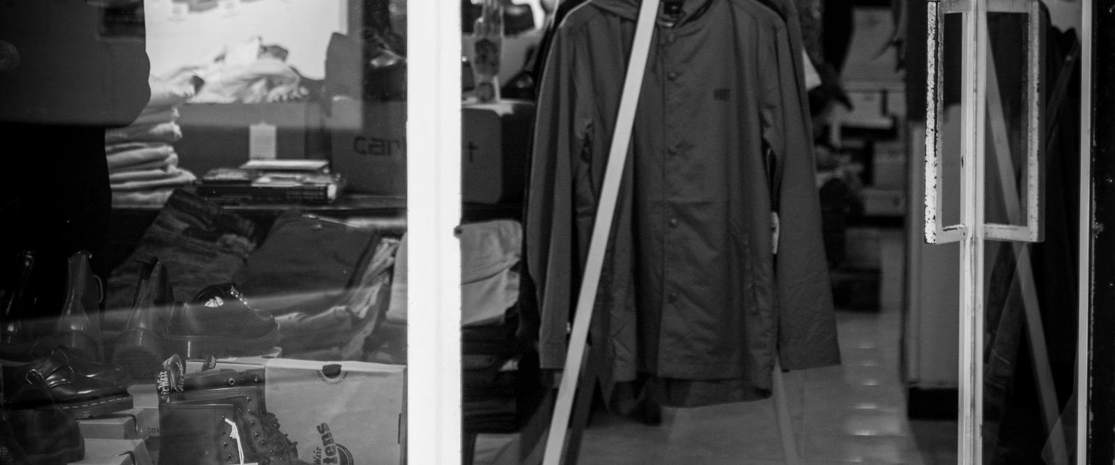 A dog sitting calmly on a lead inside a welcoming shop with a smiling owner nearby