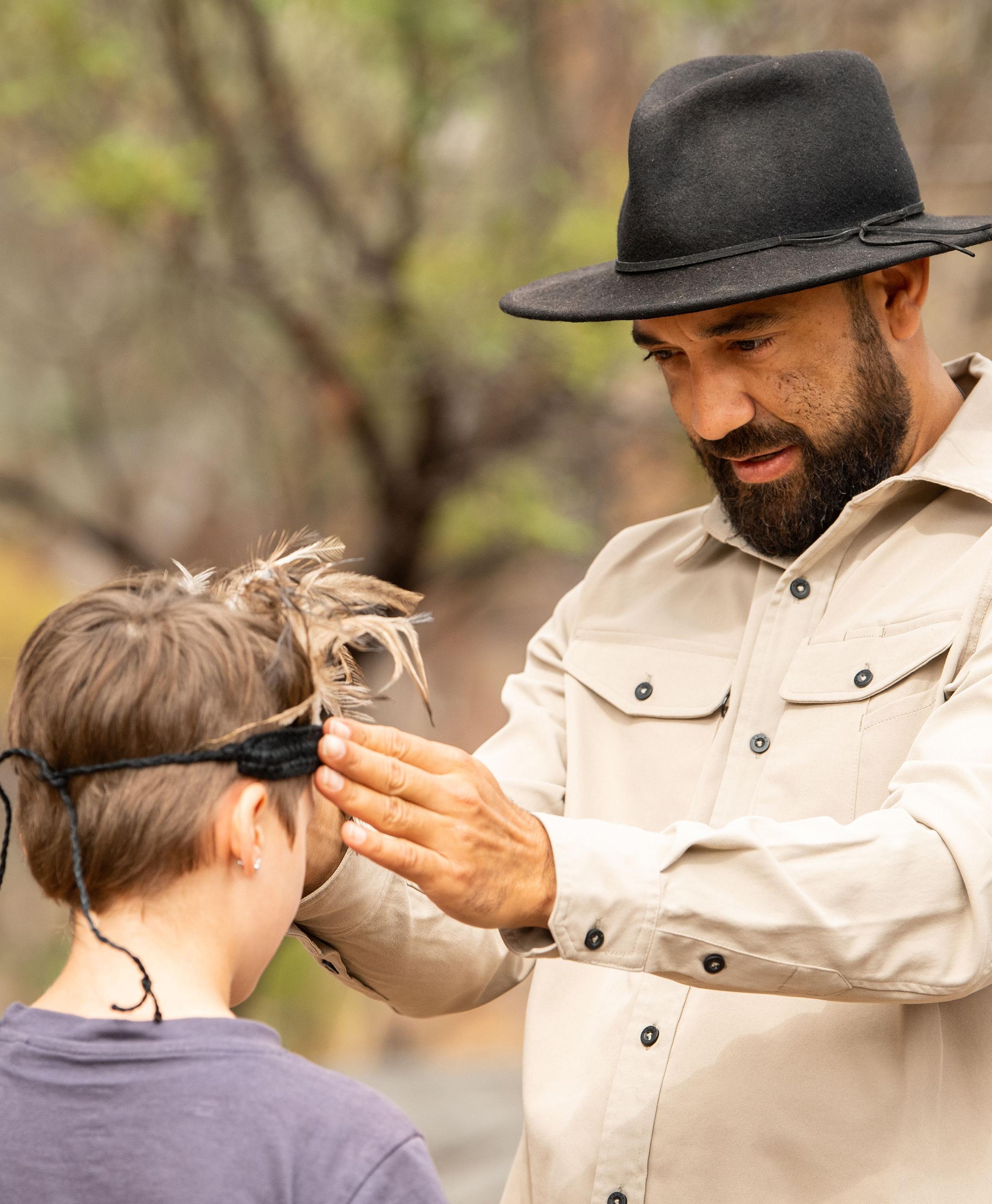 Indigenous man placing headdress on child