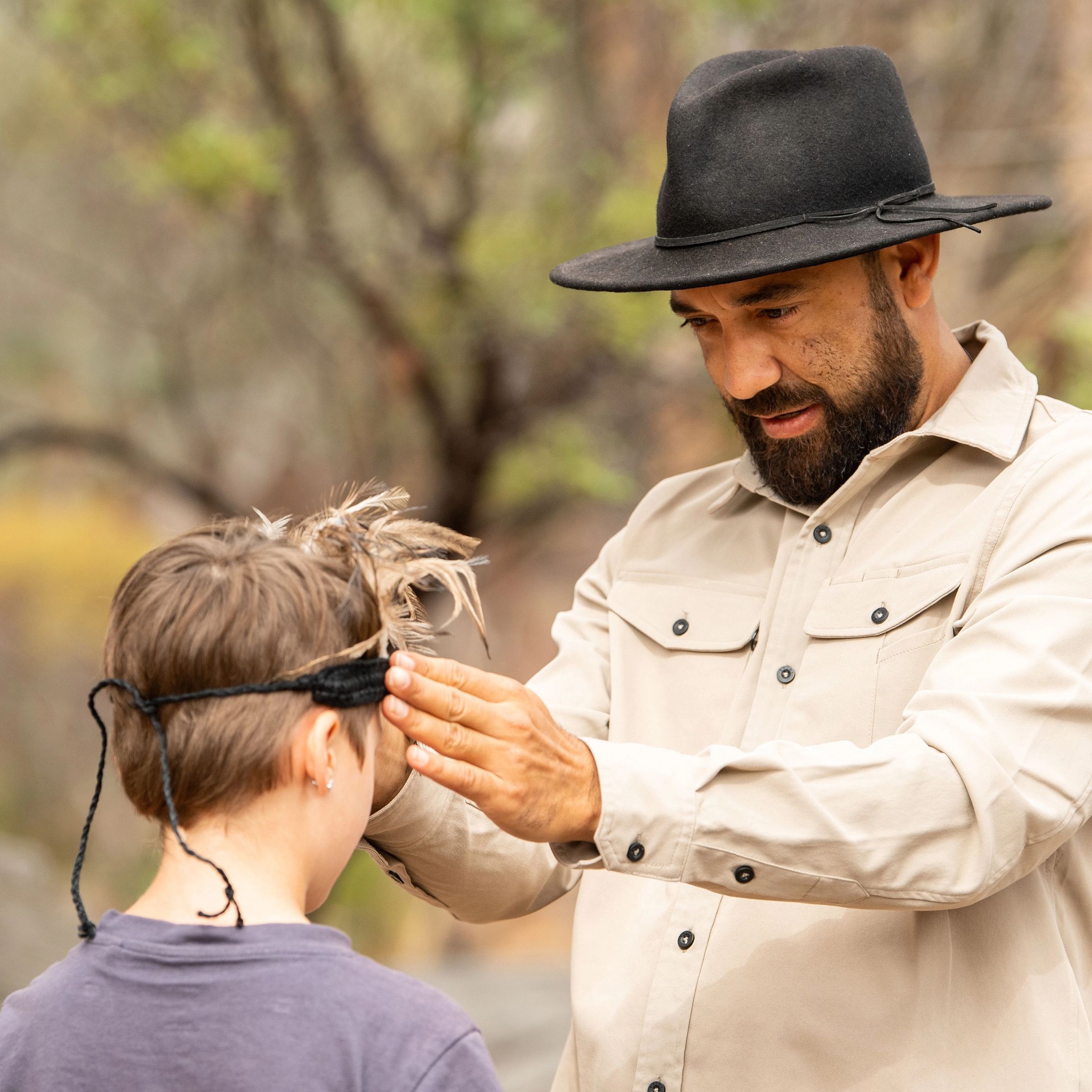 Indigenous man putting headpiece on young child