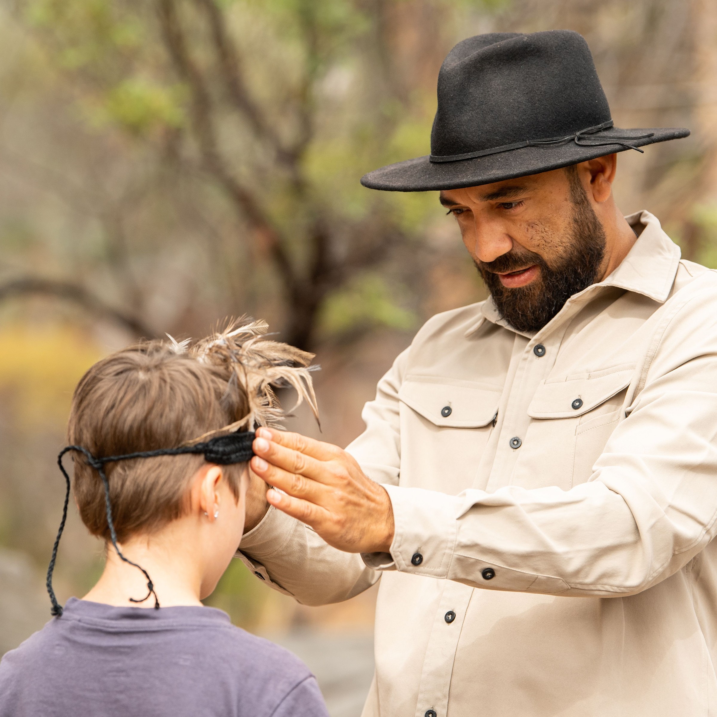 Indigenous man putting headpiece on young child