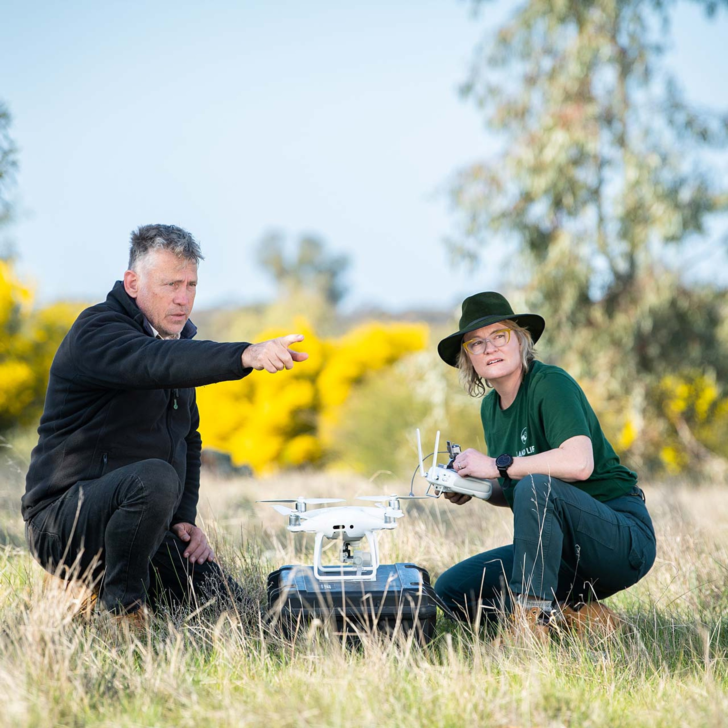 Man and woman with drone on rural land