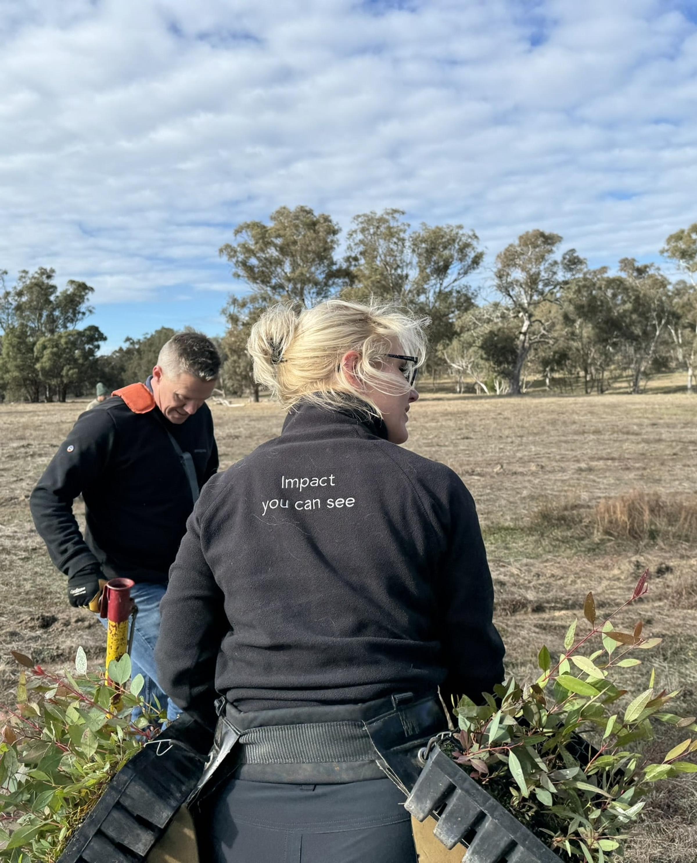 Two people planting saplings on degraded land