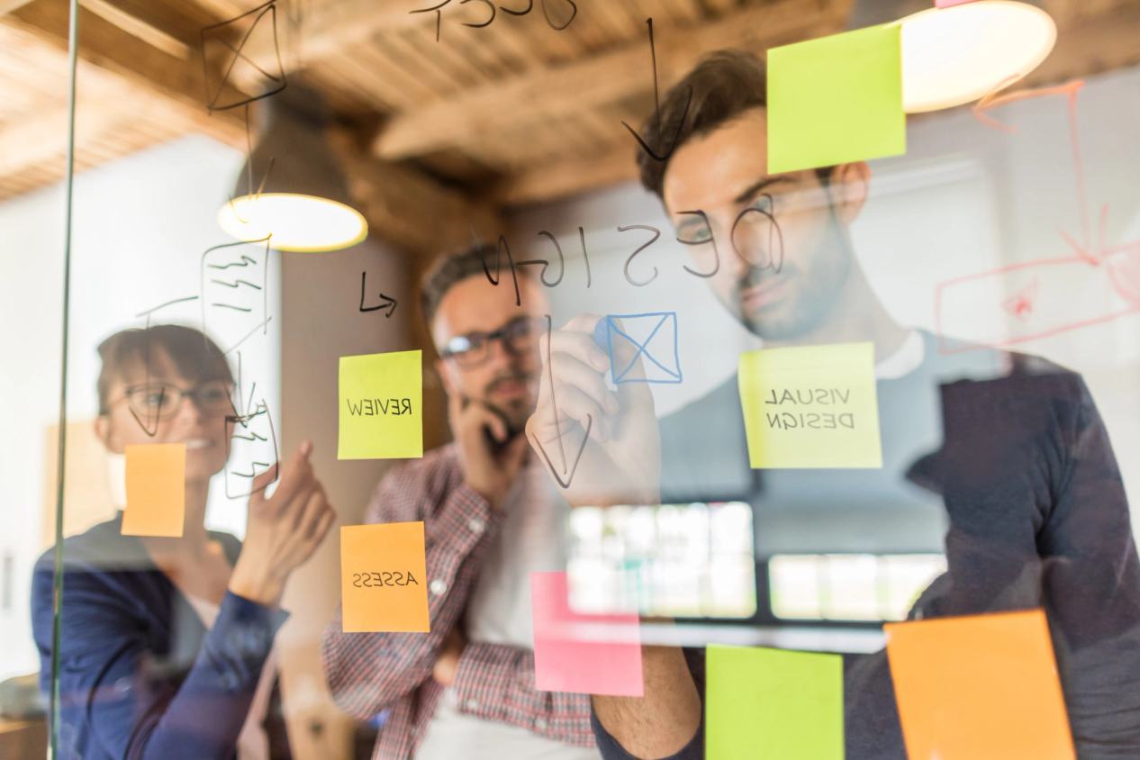 three people infront of transparent panel making notes