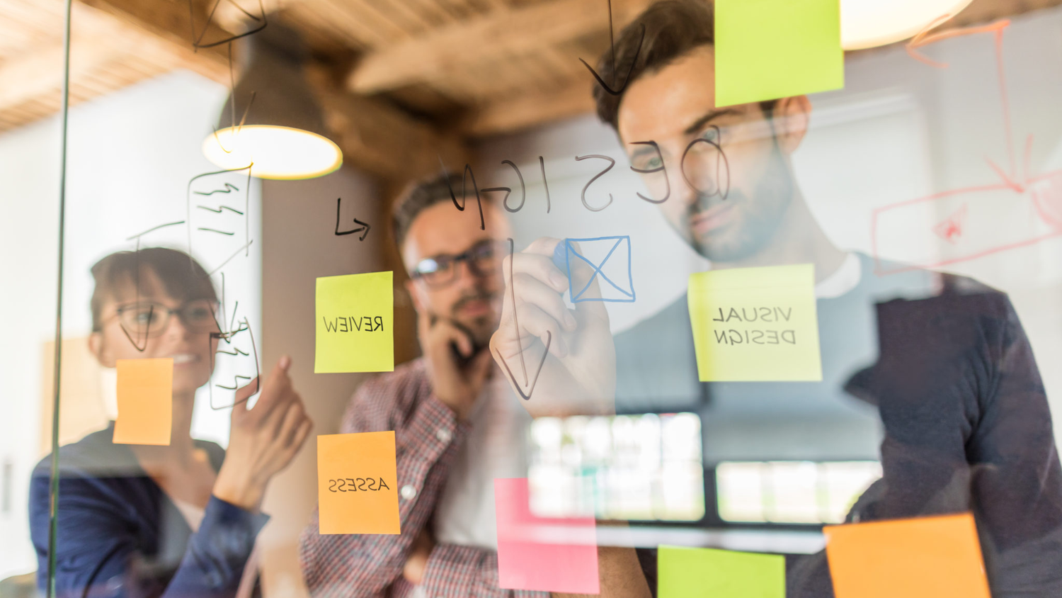 three people infront of transparent panel making notes