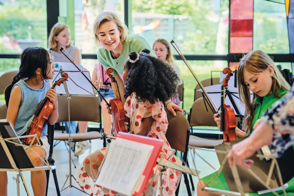 Foto van de directrice van het fonds bij een orkest van jonge kinderen