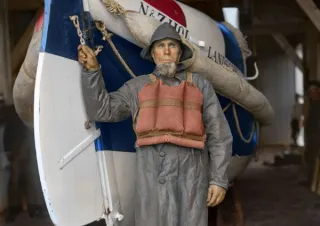 Een beeld van een reddingswerker naast een schip 