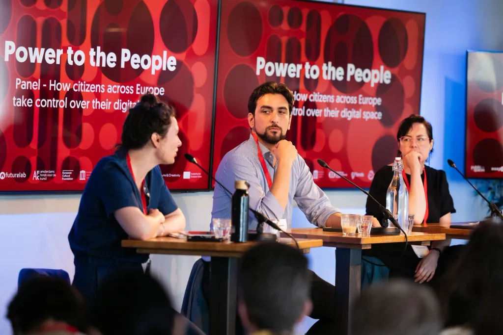 Drie personen op een conferentie op een podium in gesprek