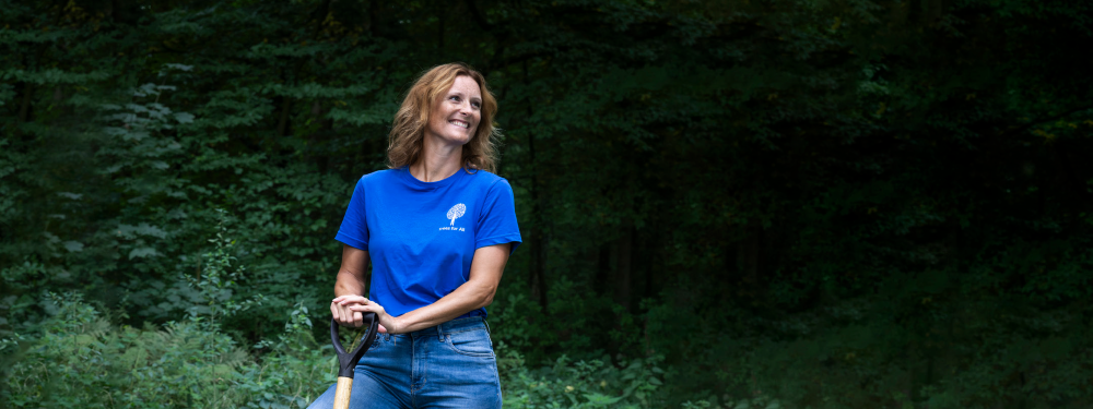 Lachende vrouw met een schep in haar hand en Trees for All T-shirt aan