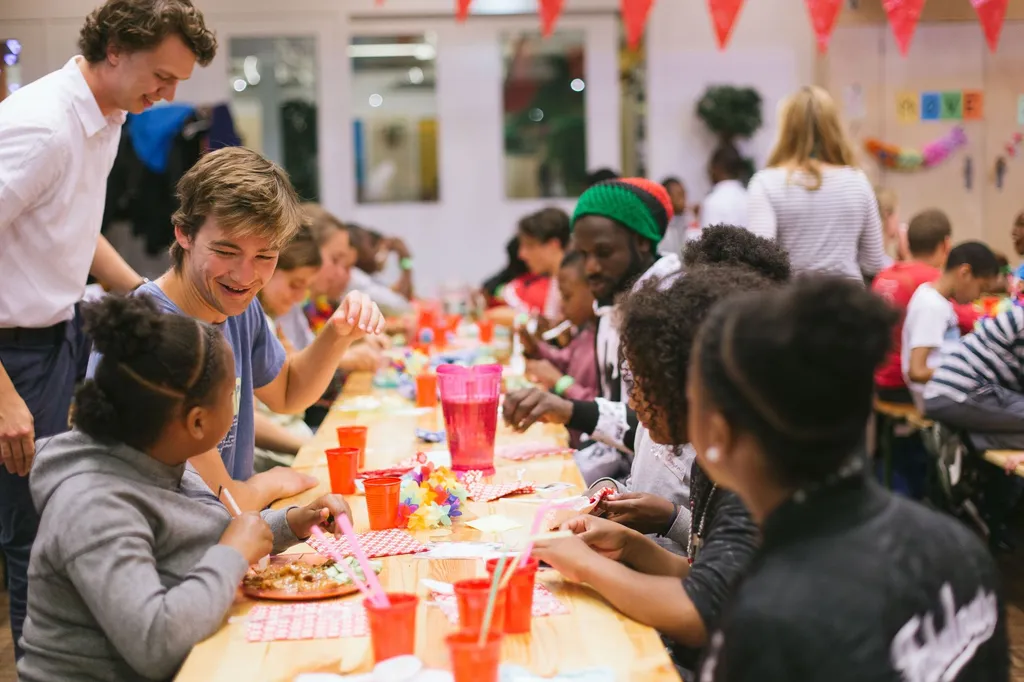 Een buurtfeestje met kinderen aan een lange tafel