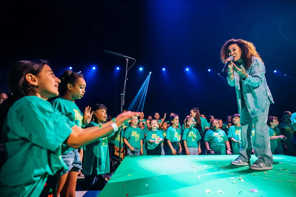 Een zangeres op het podium omringd door kinderen