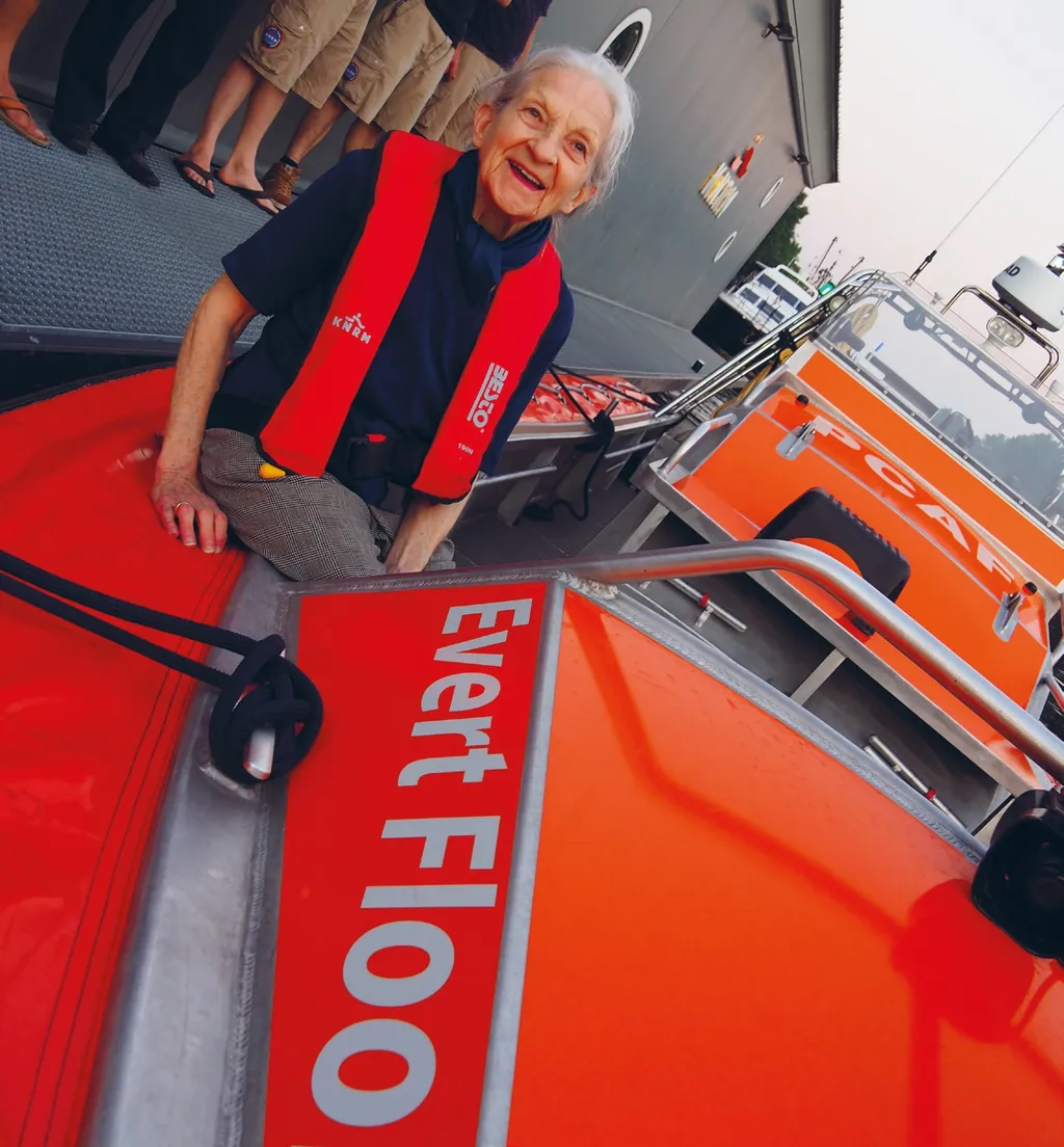 Foto van mevrouw Floor bij de reddingboot Evert Floor die zij schonk aan de KNRM ter nagedachtenis aan haar overleden man. 