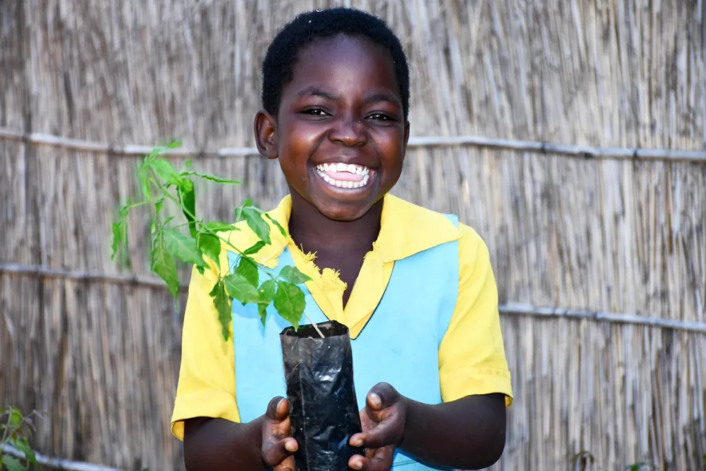 Afrikaans jongetje houdt lachend een plant vast