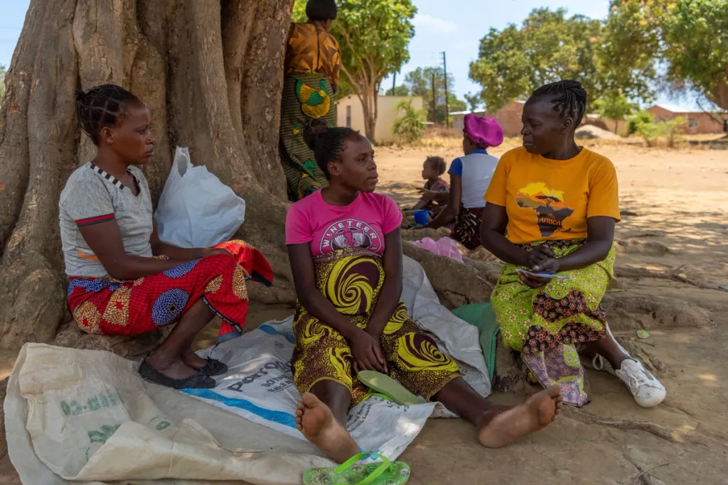 Foto van drie zwangere vrouwen in Afrika die onder een boom zitten