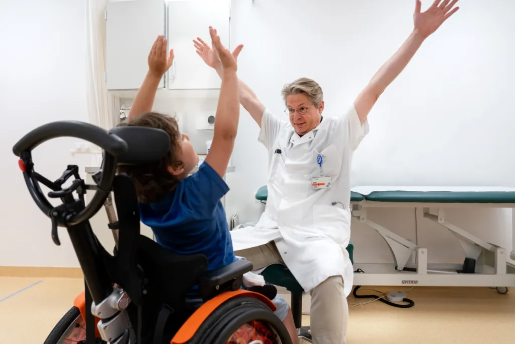 Kind in een rolsteol en arts sporten samen in een sportzaal