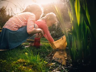 Twee kindjes vissen in een vijver naar waterdiertjes