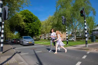 Twee personen met een blinde stok steken de straat over