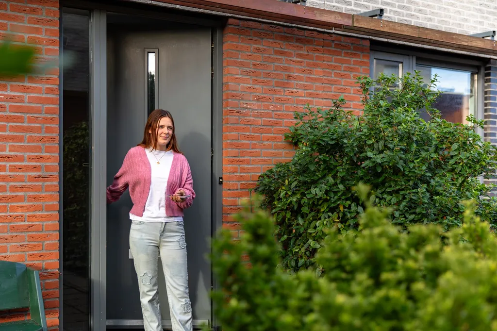 Een jonge vrouw stapt de deur uit naar buiten met autosleutels in haar hand