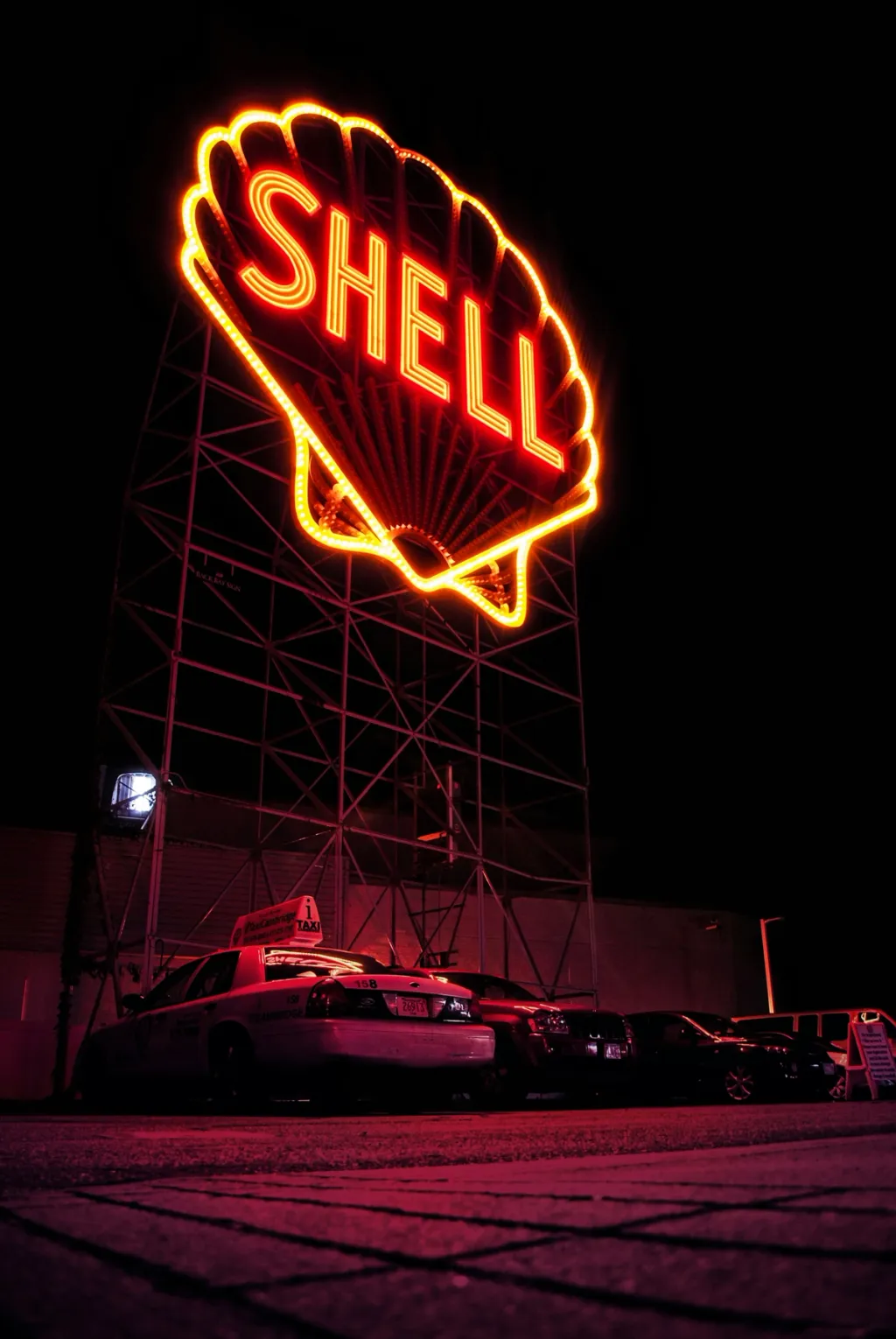 A parking lot at night with a Shell neon sign