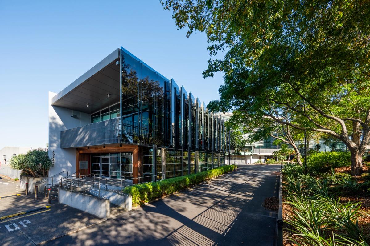 Modern building with glass facade and surrounding greenery at 433 East Tamaki Road on a sunny day. Modern building with glass facade and surrounding greenery at 433 East Tamaki Road on a sunny day.