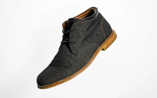 Gray and brown suede lace-up shoe on a plain background