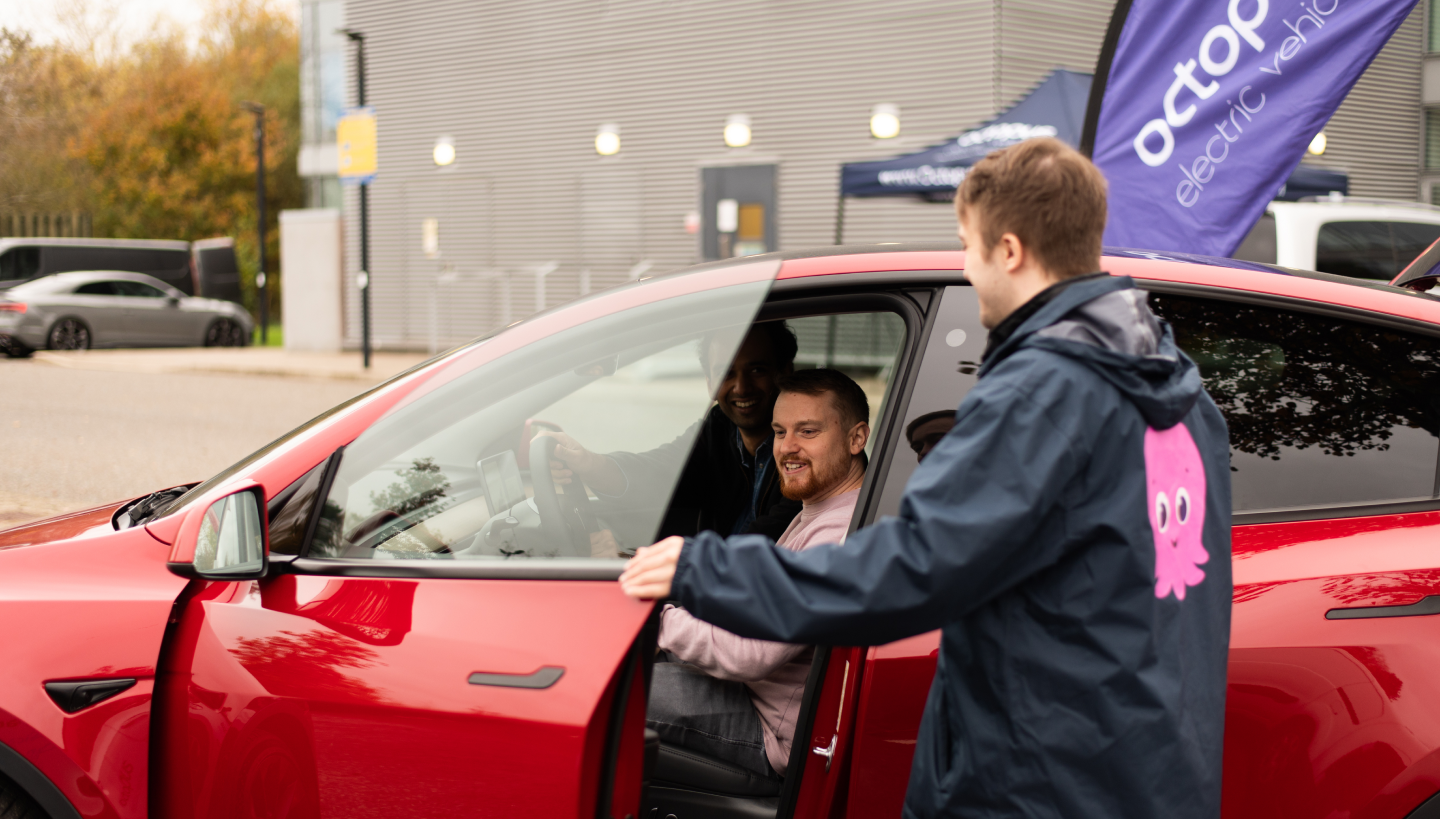 Two men looking at Red Tesla Model 3