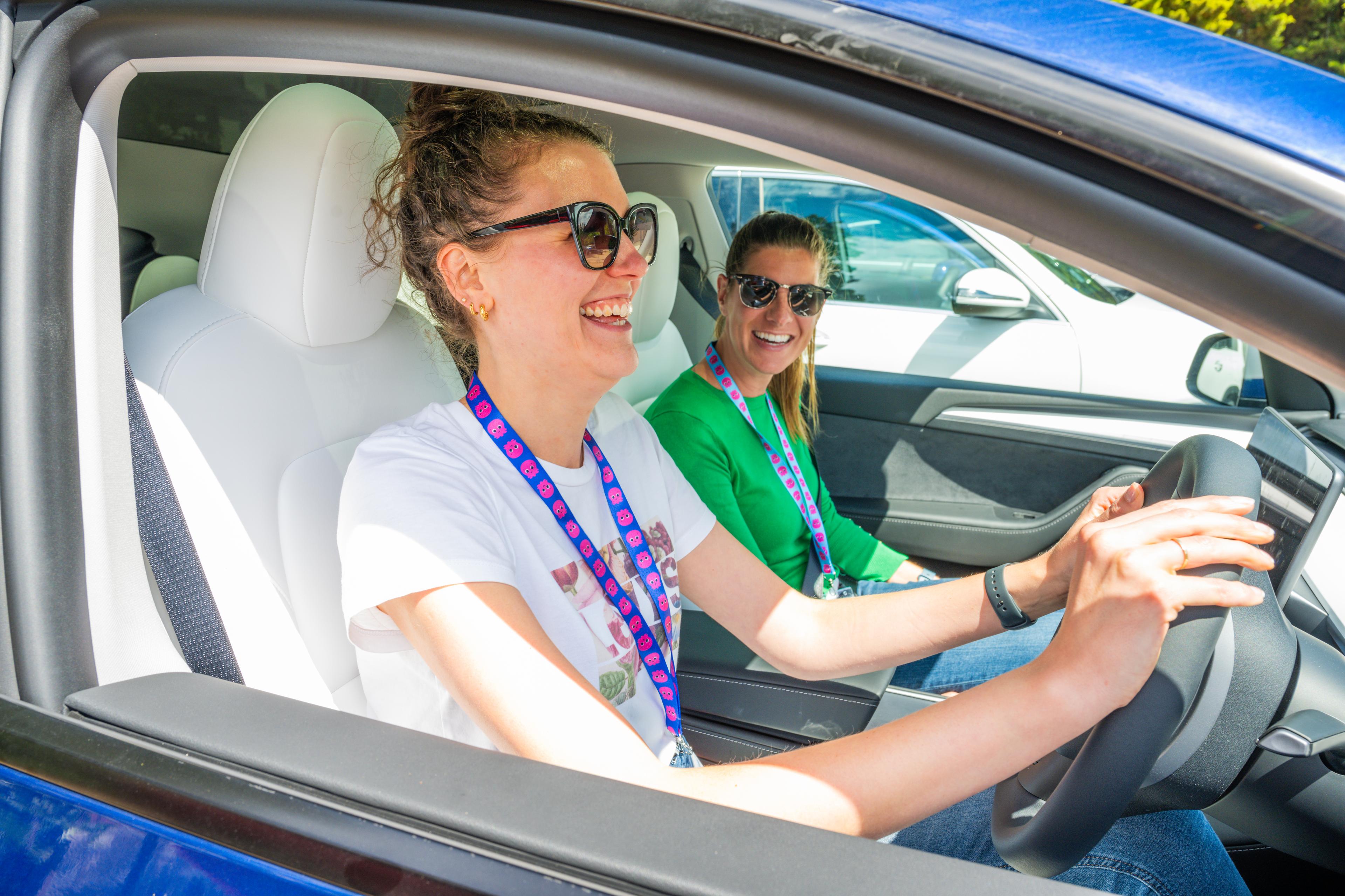 Two smiling women test driving an EV