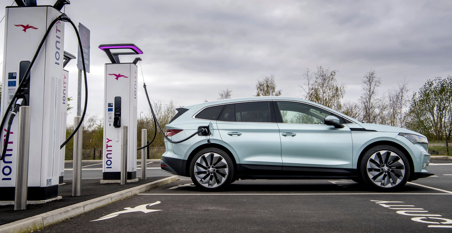 Silver car shown sideways plugged in Ionity rapid charger at motorway services