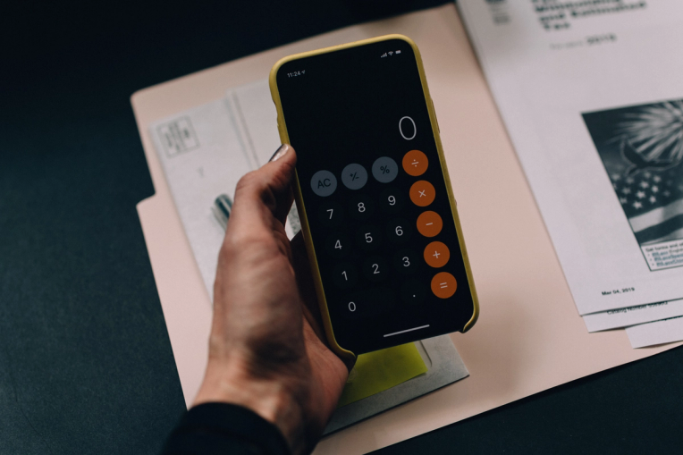 iPhone calculator held in front of paperwork 