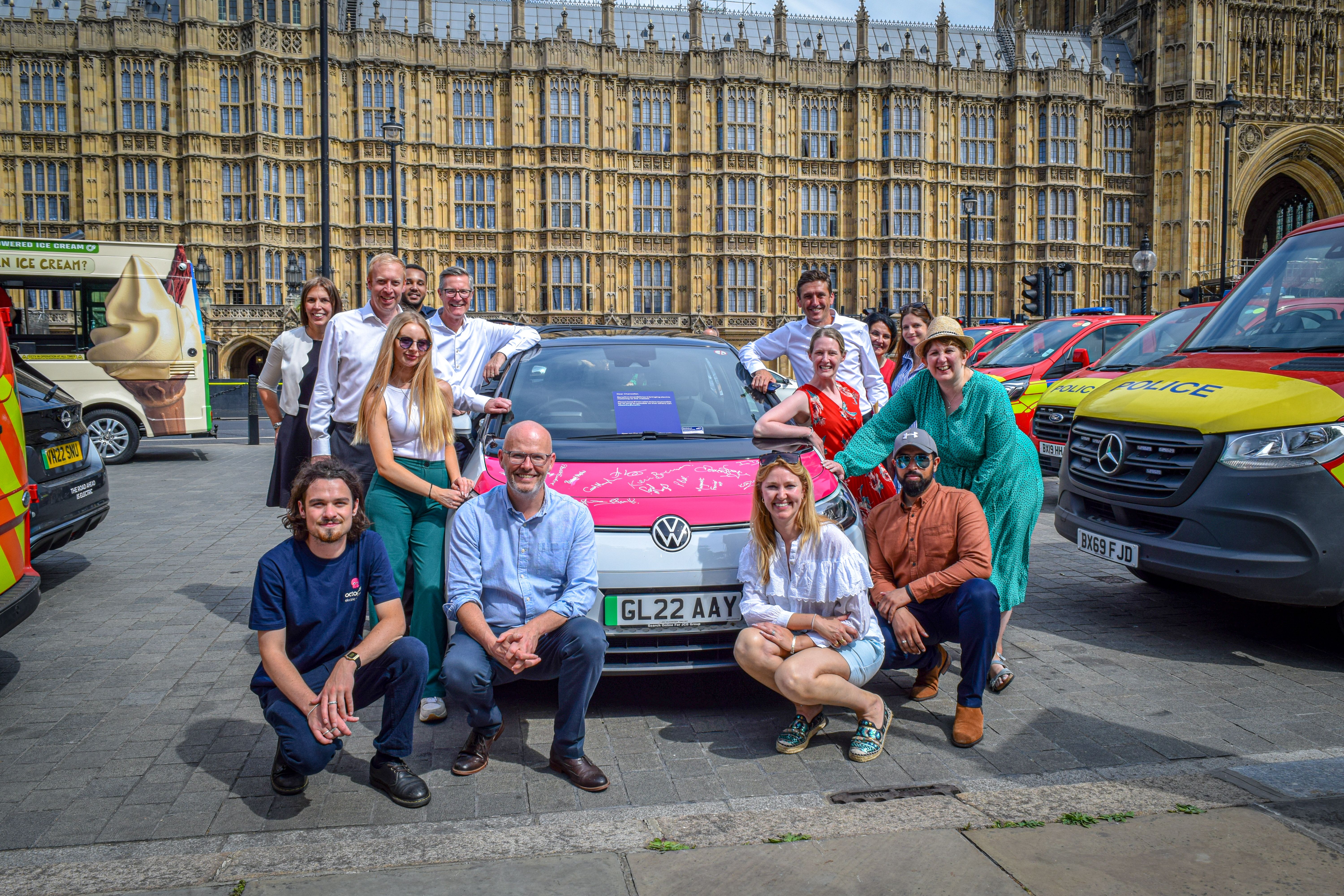 A Happy Octopus Electric Vehicles team in-front of Westminster posing next to an electric vehicle