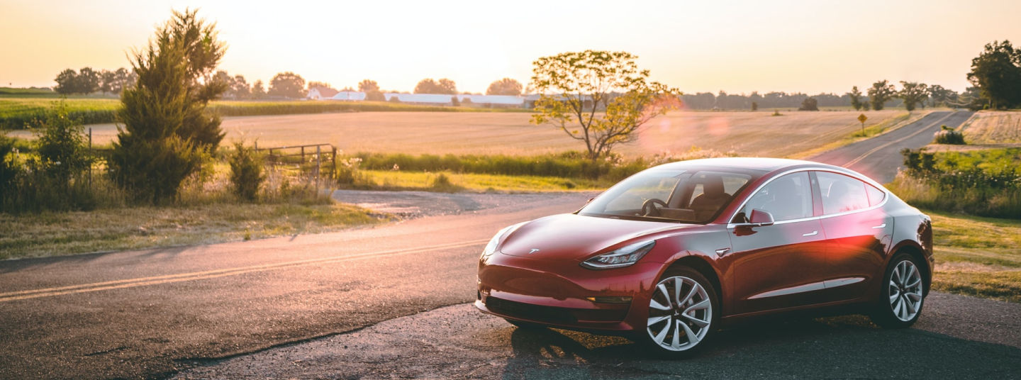 Red Tesla Model 3 parked at side of road