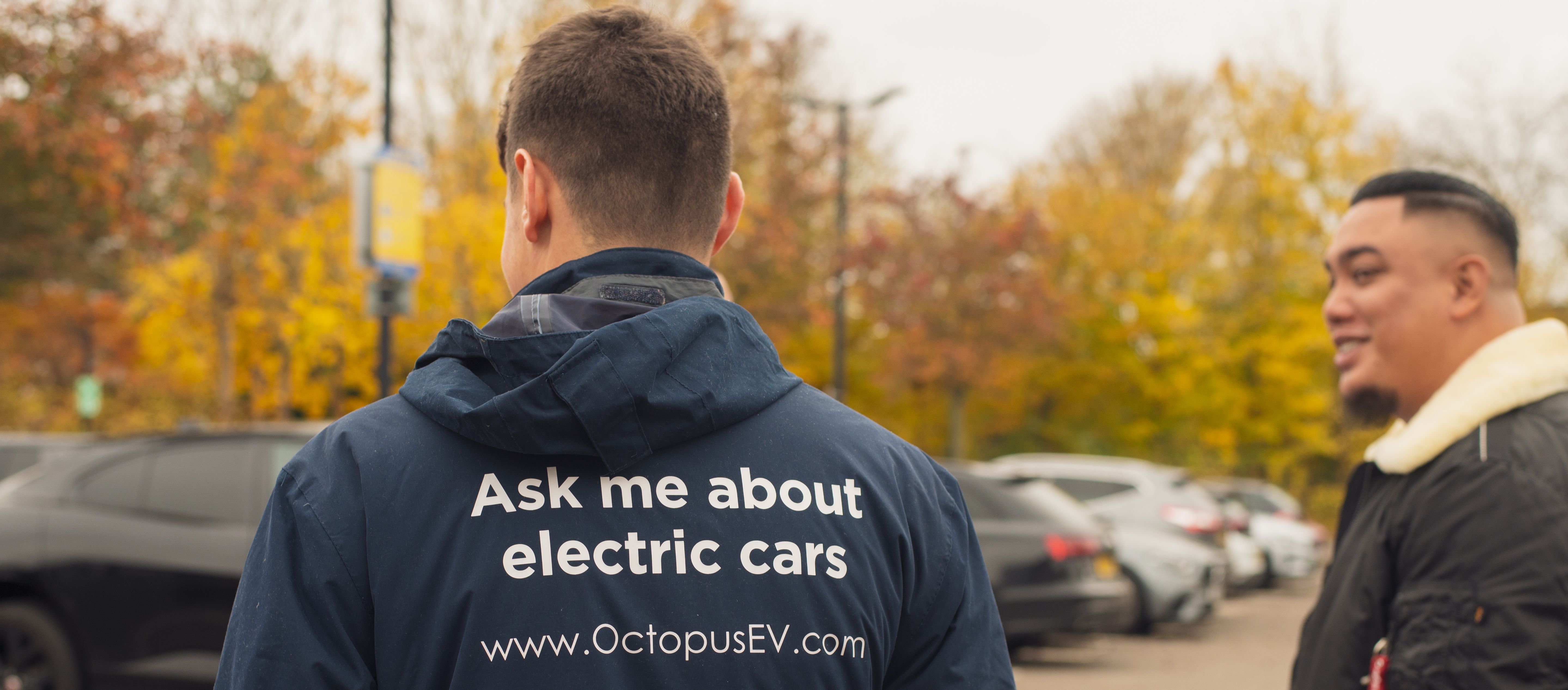 Octopus electric vehicles specialist talking to a customer with cars in the background